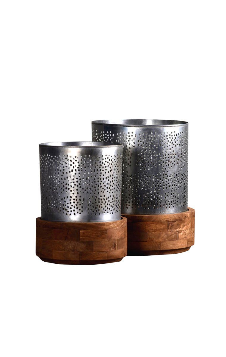 Villa 2 Manado Hurricane Medium Candleholder Features "Jaali" Votive where candlelight seeps through small holes creating a lovely ambiance. The product can hold up to 3"Dia Candle. The Votive combines Brushed Antique Zinc Finish combined with Weathered Finish Solid Wood Base.